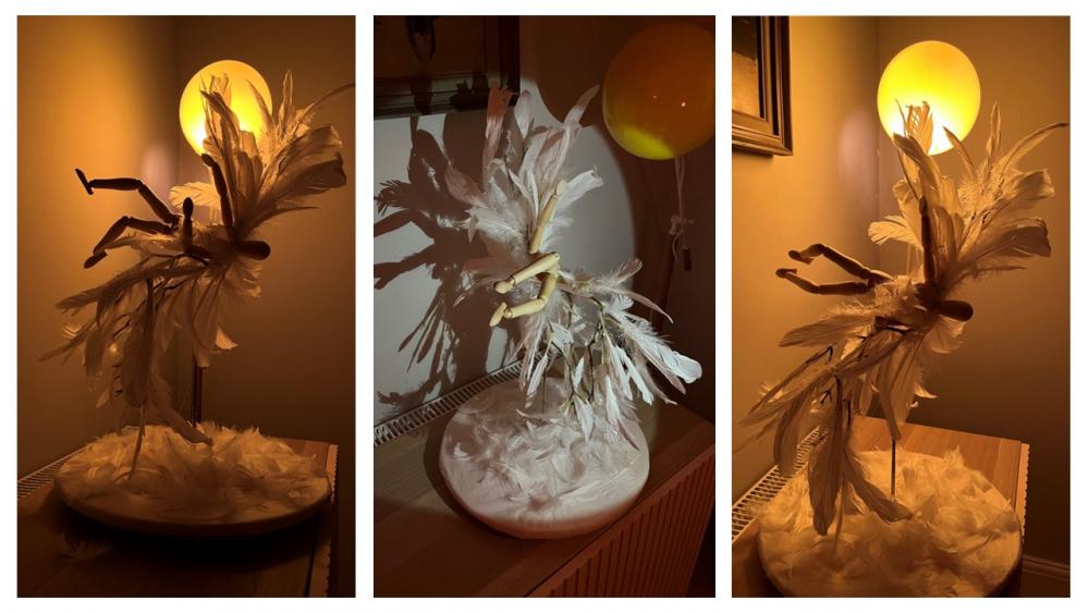 A dramatic model showing Icarus' fall. A human figure is shrouded in feathers and is photographed from different angles with dramatic lighting.